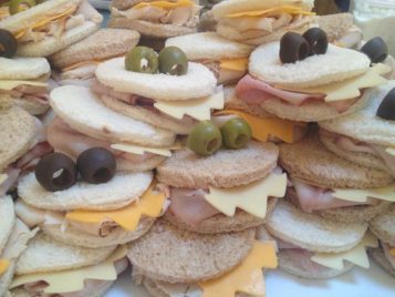 A pile of assorted sandwich triangles with various fillings, topped with green and black olives, becomes a scene of monster madness!