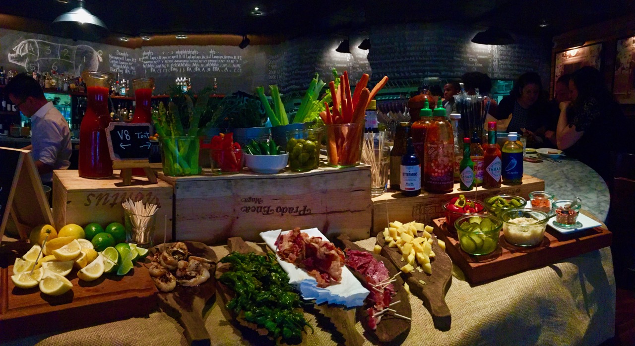 A vibrant and cozy bar scene in Stamford, CT, with a well-stocked bloody mary station complete with an array of condiments and garnishes, patrons enjoying the ambiance.