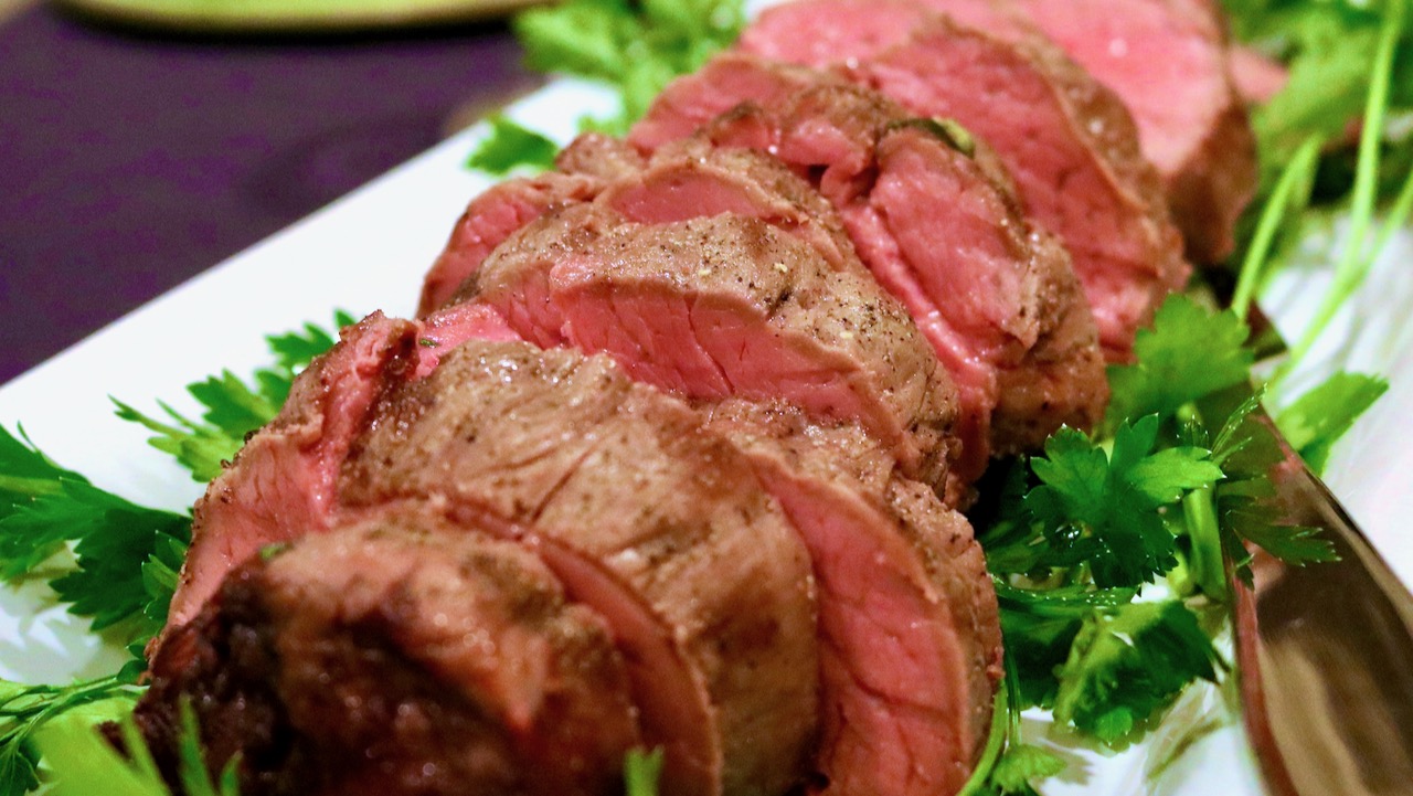 Beef Tenderloin cooked perfectly medium rare and sliced on a platter.