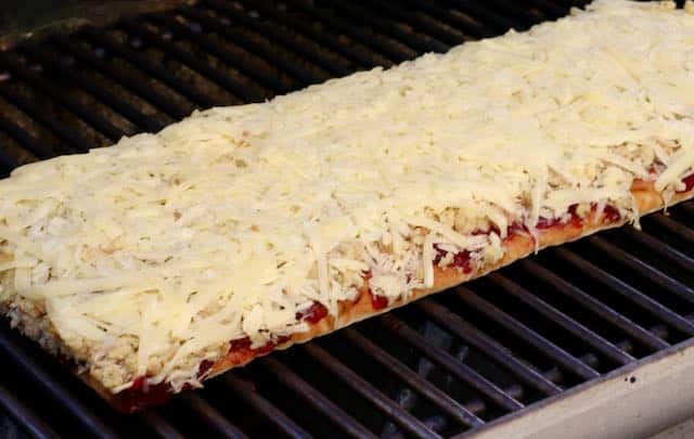 flatbread layered with cranberry sauce, shredded turkey, stuffing & cheese on grill