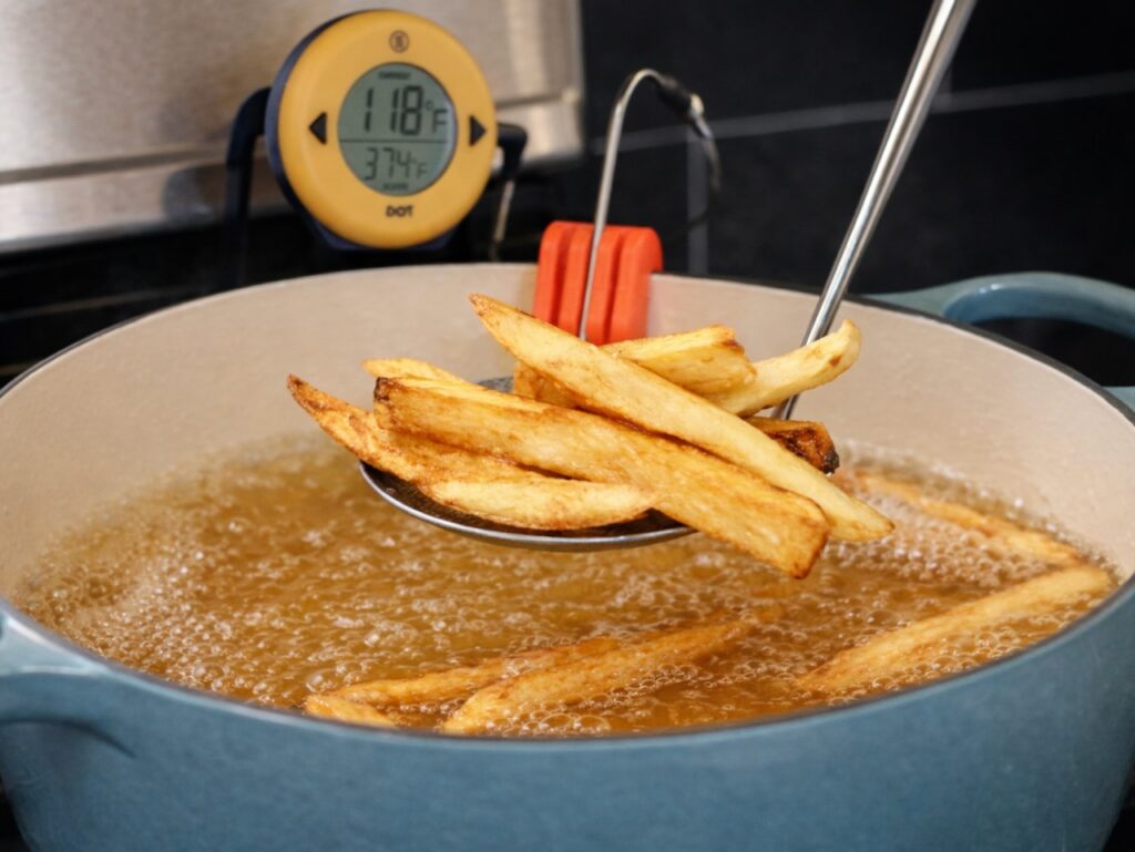 French Fries in hot oil for making Traditional English Chips to serve with Fish & Chips