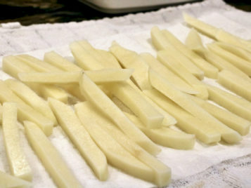 Raw Russet potatoes sliced into fries and ready to fry