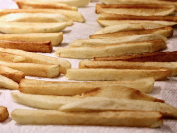 Homemade french fries draining on paper towel