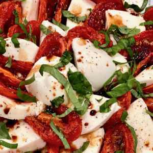 Platter with roasted plum tomatoes with fresh mozzarella and basil