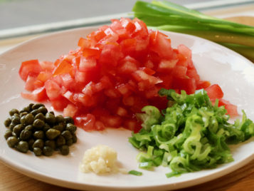 chopped tomatoes, scallions, garlic and capers on a plate