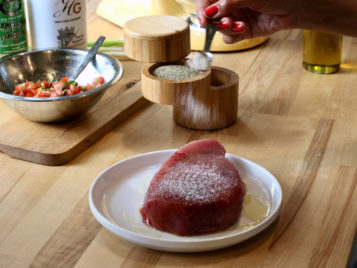 tuna steak being seasoned with salt