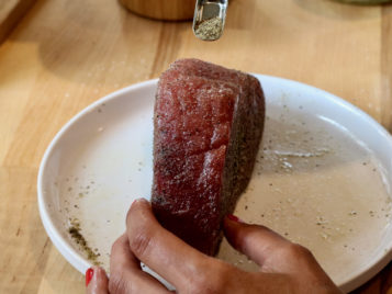 Salt and pepper going onto tuna steak