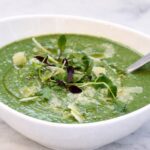homemade broccoli soup recipe in a white bowl with garnish