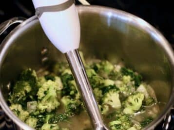 Cooked broccoli in a stock pot with an immersion blender