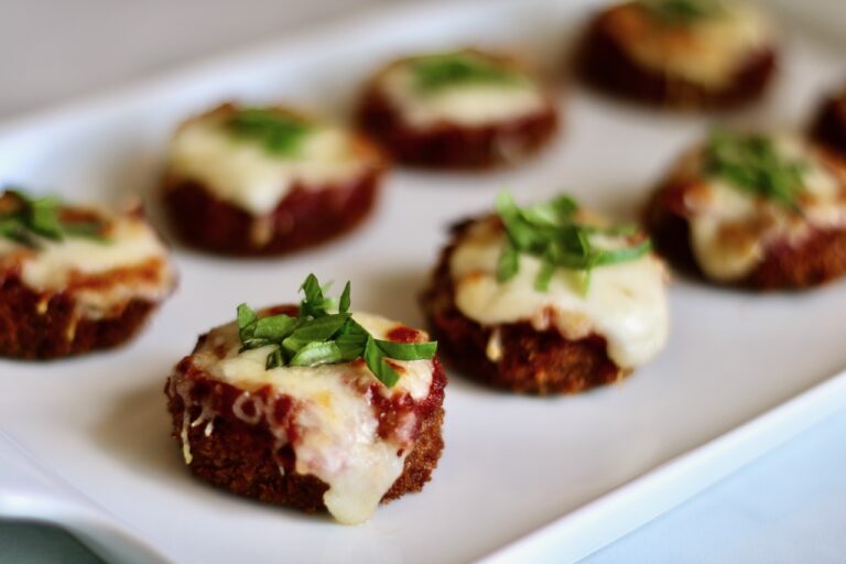 Mini Eggplant Parm garnished with basil on a serving tray- feature Image