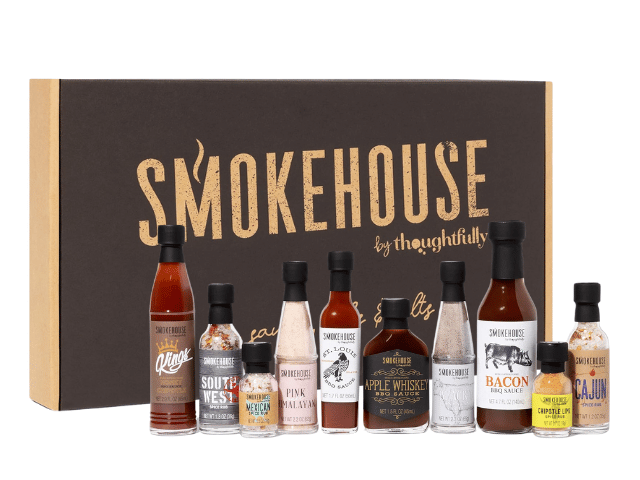 A variety set of eight hot sauces and seasonings labeled Smokehouse by Thoughtfully is displayed in front of the original rectangular packaging box. The sauces come in assorted small bottles with different labels and colors.