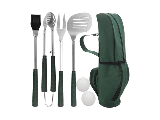 A set of stainless steel barbecue tools, including a basting brush, tongs, fork, spatula, and slotted spatula with green handles, neatly arranged next to a green backpack-style carrying case. Two white golf balls are also placed beside the bag.