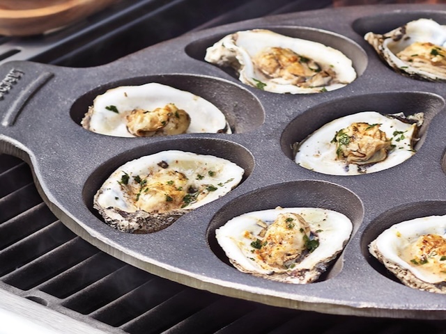 cast iron oyster tray with on the grill with cooked oysters
