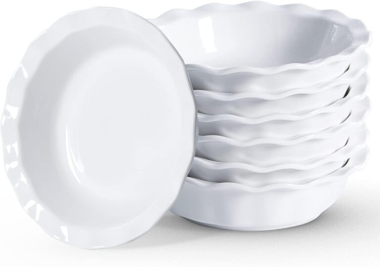 Six stacked white ceramic dishes with fluted edges; one dish is placed in front, leaning.