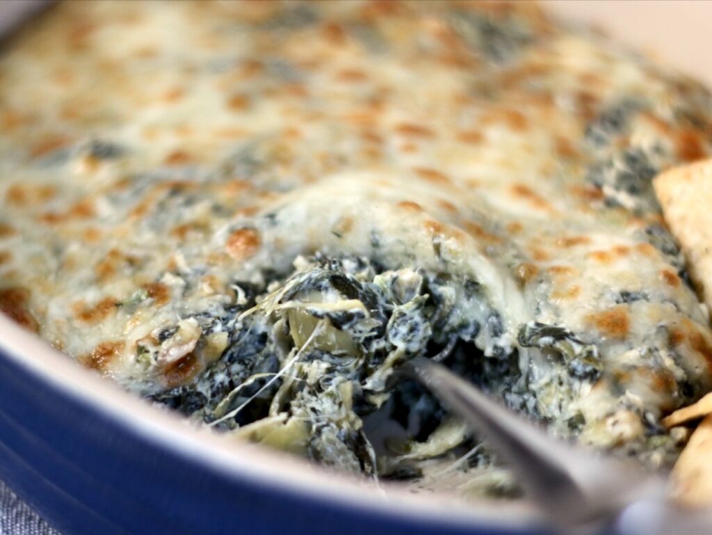 Hot Spinach and artichoke dip in a blue le crusset oval baking dish