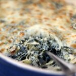 Hot Spinach and artichoke dip in a blue le crusset oval baking dish