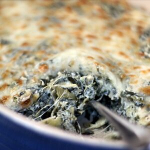 Hot Spinach and artichoke dip in a blue le crusset oval baking dish