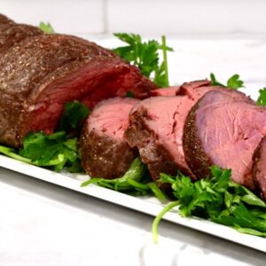 Ina Garten's slow Roasted Beef Tenderloin on a platter and sliced