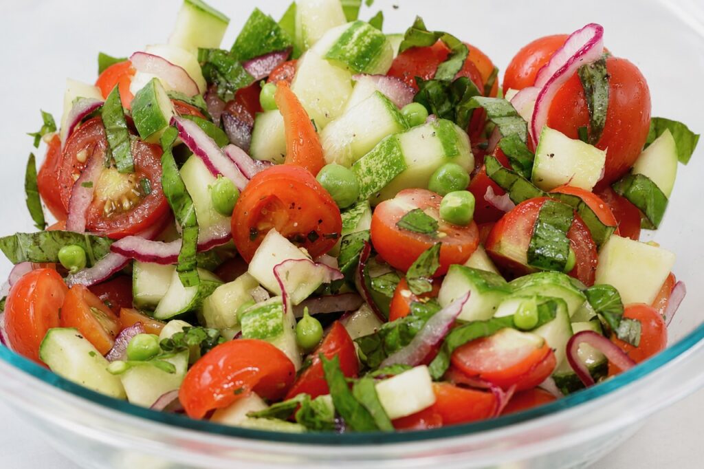 summer tomato cucumber basil salad with fresh peas, and herbs