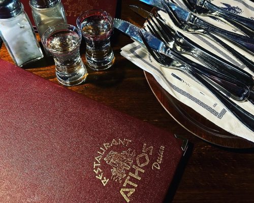 Athos Restaurant menu with 3 place settings, salt, pepper and shot glasses