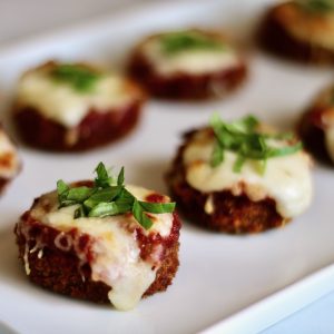 Mini Eggplant Parm garnished with basil on a serving tray- feature Image